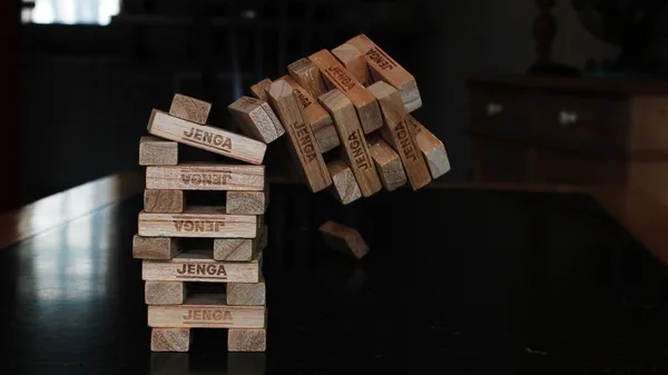 A tower of Jenga blocks captured mid-way through the top of the tower falling over.